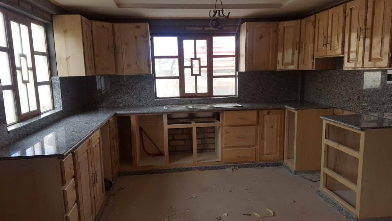 Cocina con mesones de mármol gris y muebles de madera